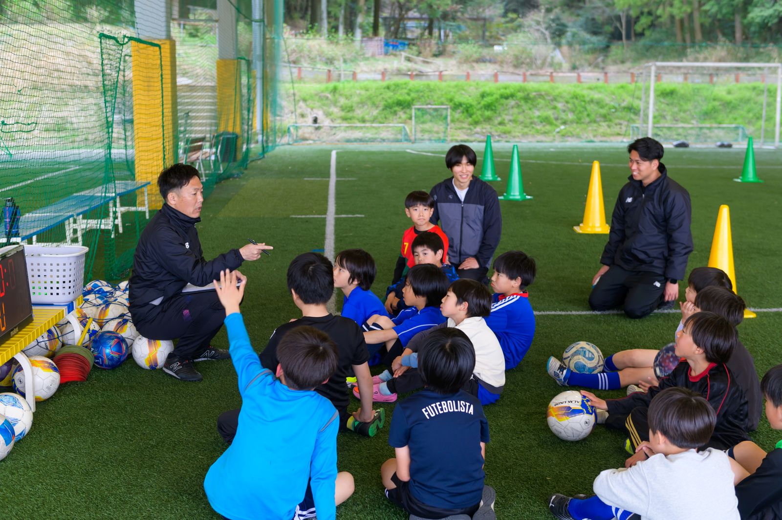 子どもたちと同じ目線にしゃがんで話す西口コーチ