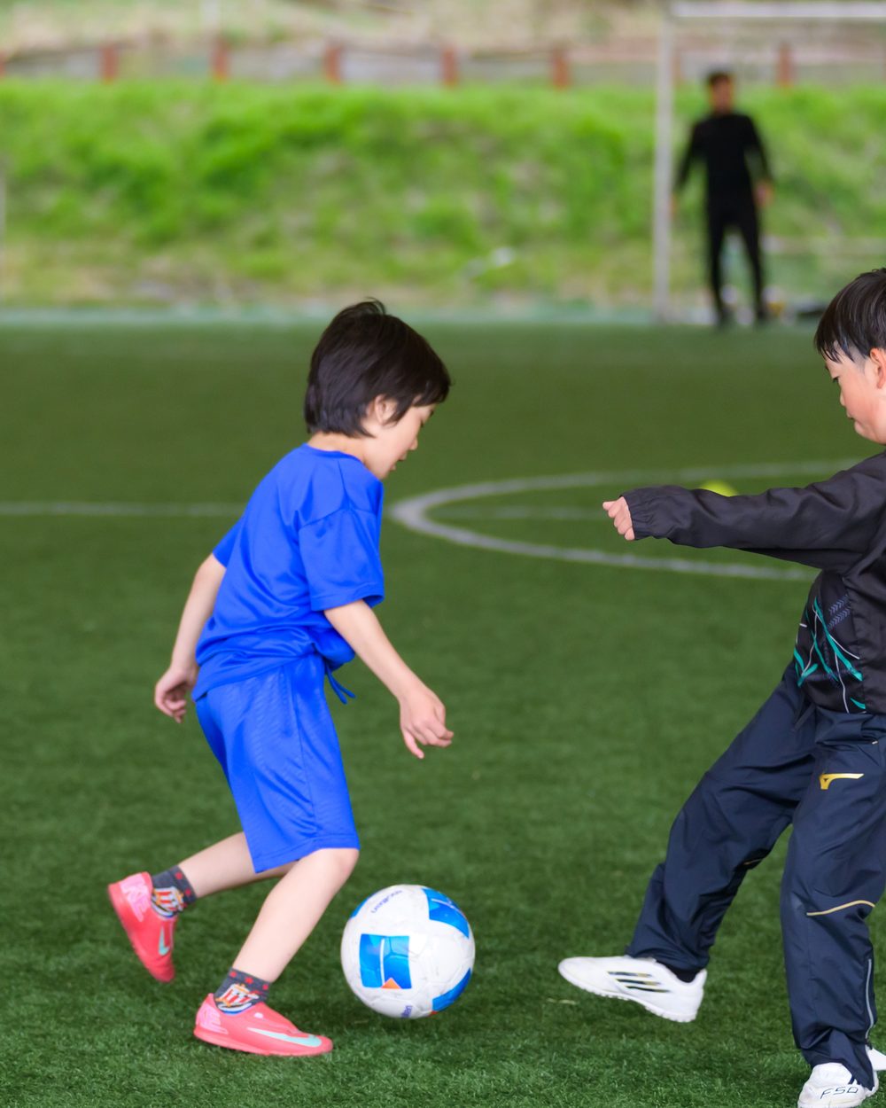 ボールを持って年上の子と向き合う小さな子ども
